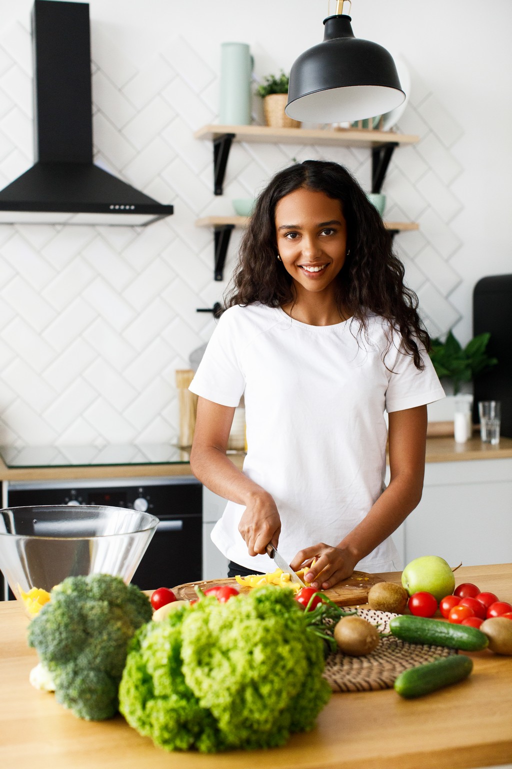 Pretty afro girl is cutting a yellow pepper and smiling Pretty afro girl is cutting a yellow pepper and smiling